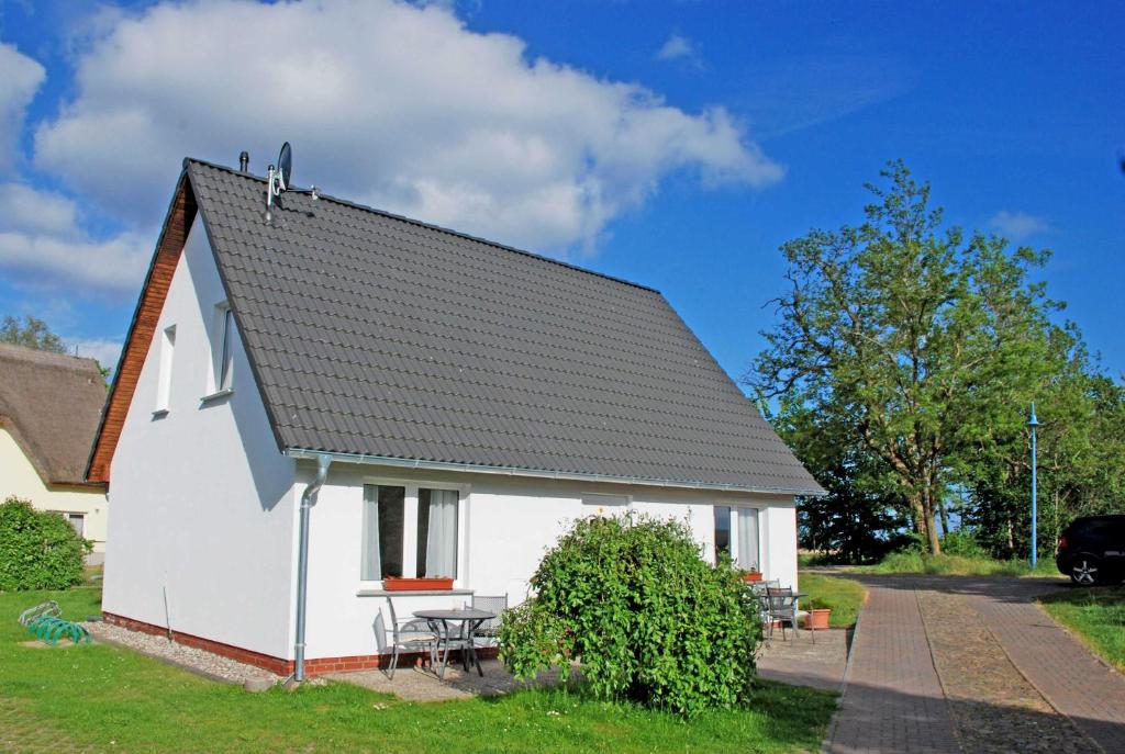 uma casa branca com um telhado preto em Ferienwohnungen im Haus am Deich em Middelhagen