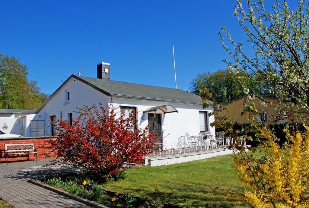 ein weißes Haus mit einem roten Busch davor in der Unterkunft NEU - Ferienhaus mit Sonnenterrasse in Ostseebad Sellin