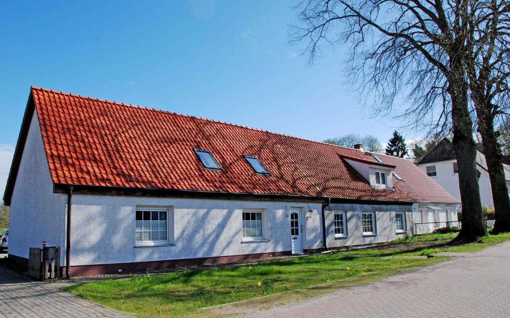 ein weißes Haus mit orangefarbenem Dach auf einer Straße in der Unterkunft Ferienwohnungen auf dem Pommernhof in Samtens