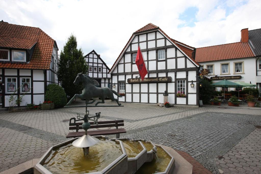 een fontein voor een gebouw met een standbeeld bij Hotel Altes Gasthaus Greve in Recke