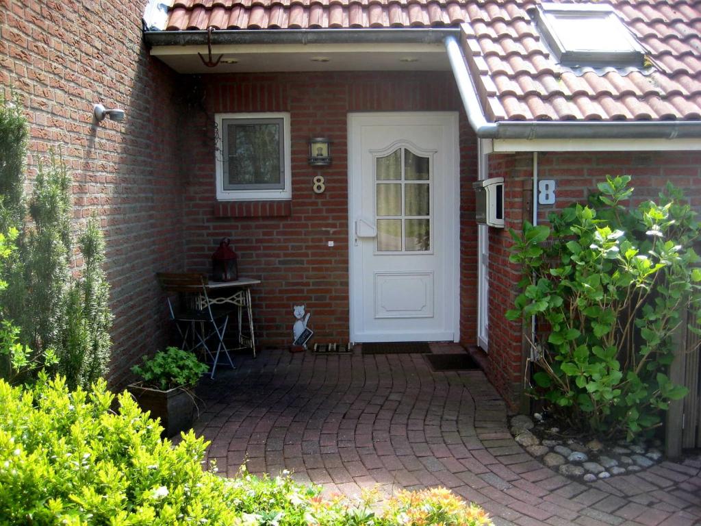 a brick house with a white door and a patio at Ferienhaus AS TO HUS in Büsum