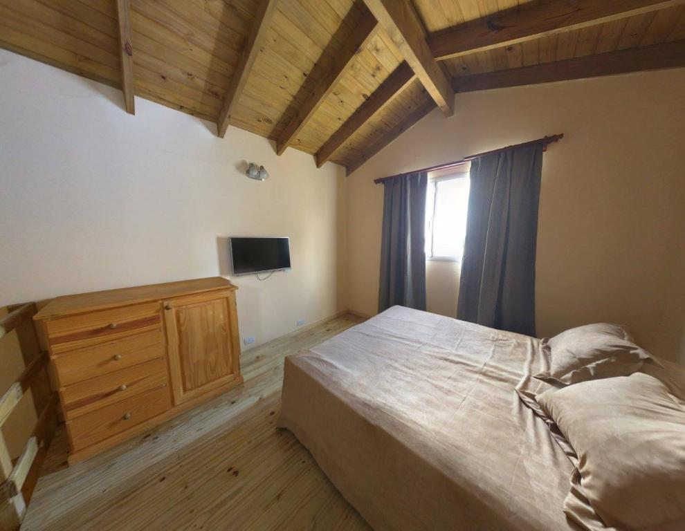a bedroom with a bed and a dresser and a window at Departamentos tandil in Tandil