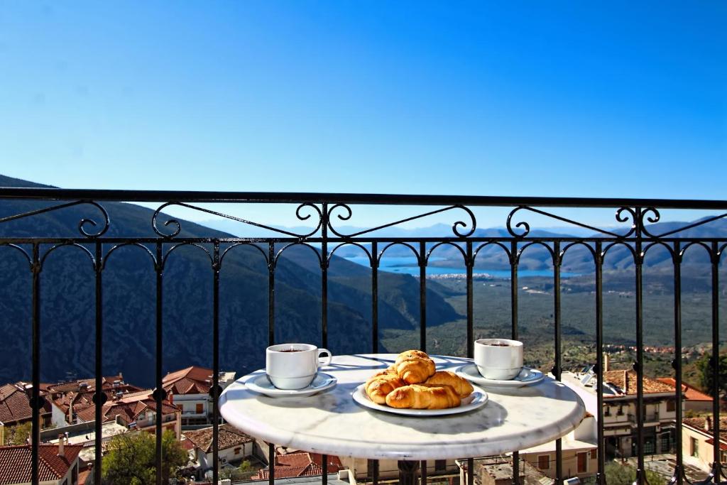 una mesa con un plato de cruasanes y tazas de café en Arion Hotel, en Delfos