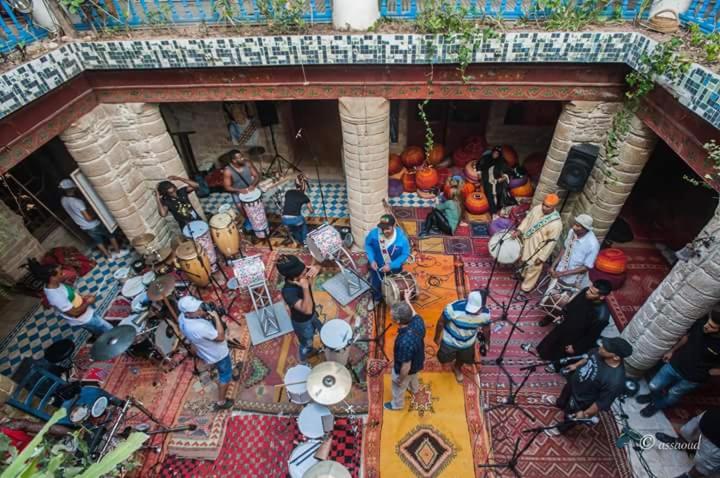 un grupo de personas de pie alrededor en un edificio en Hôtel Riad Gnaoua, en Essaouira