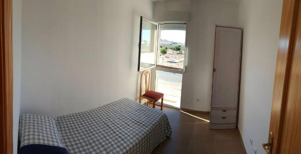 a small bedroom with a bed and a window at Apartamento in Los Urrutias