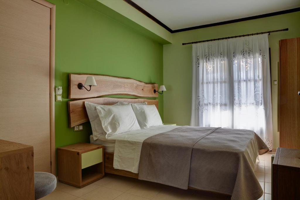 a bedroom with a bed with green walls and a window at Elaion Terra Boutique Guesthouse in Theologos
