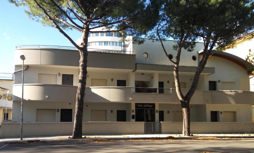 リニャーノ・サッビアドーロにあるApartment in Lignano Sabbiadoro 31384の目の前に木々が植えられた白い大きな建物