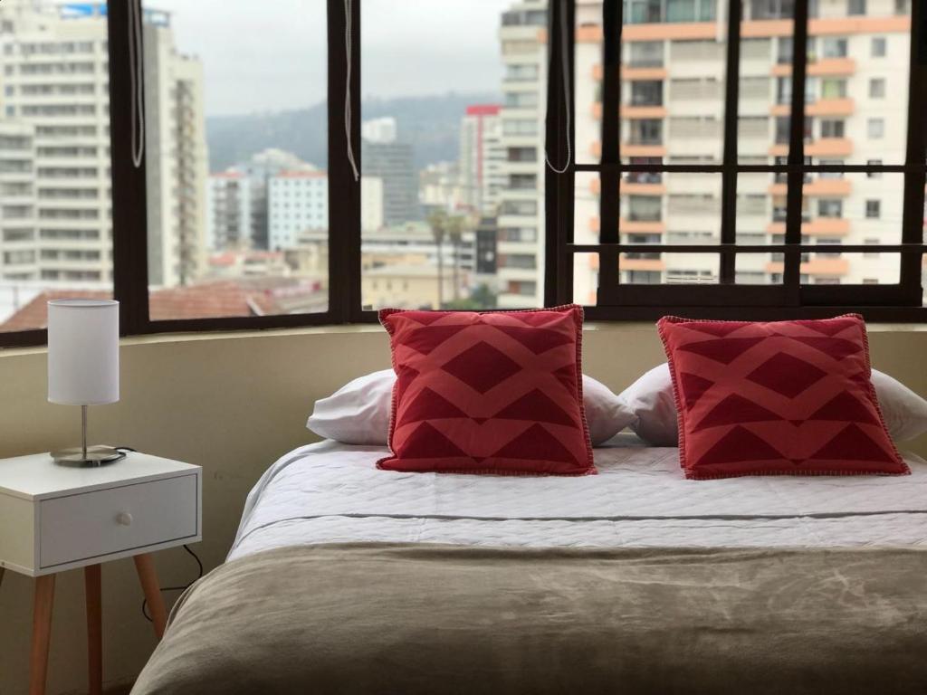 een slaapkamer met een bed met rode kussens en een raam bij Hostal My House in Viña del Mar