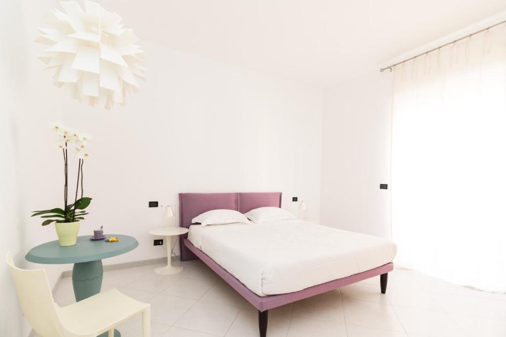 コンヴェルサーノにあるB&B Casa Larucciaの白いベッドルーム(ベッド1台、テーブル、椅子付)