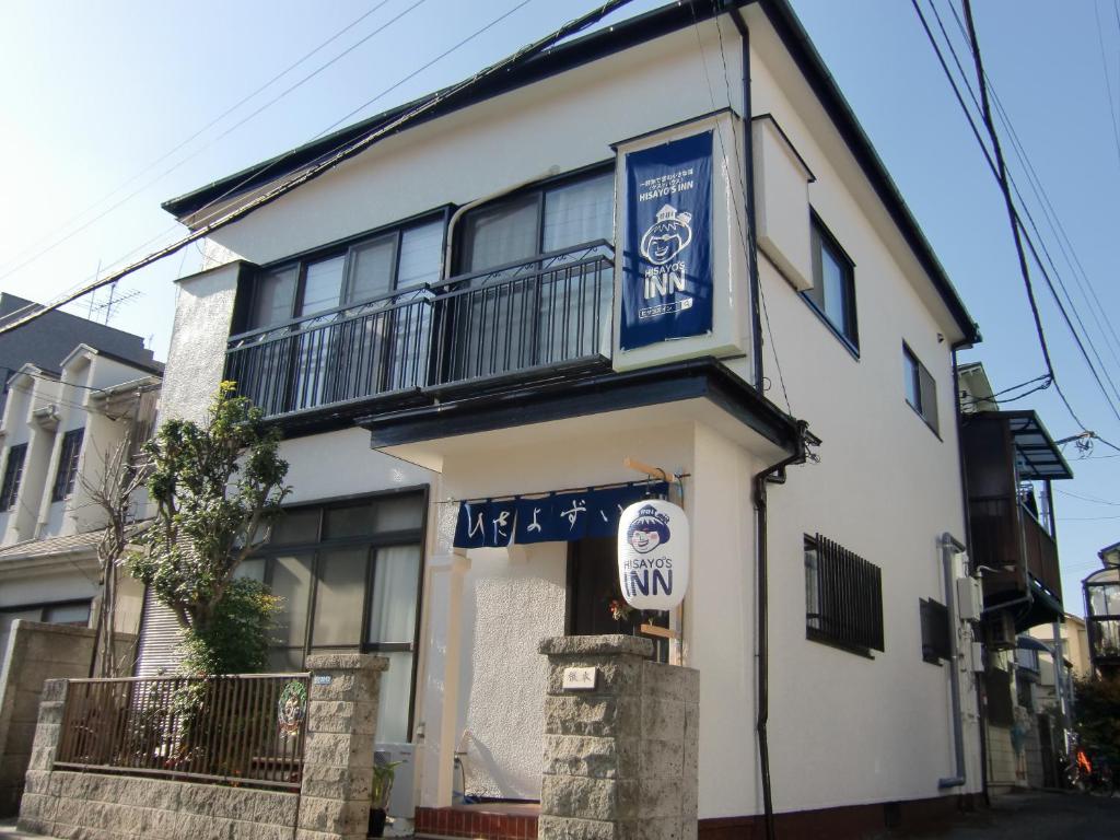 um edifício branco com um sinal azul em HISAYO'S INN em Tóquio