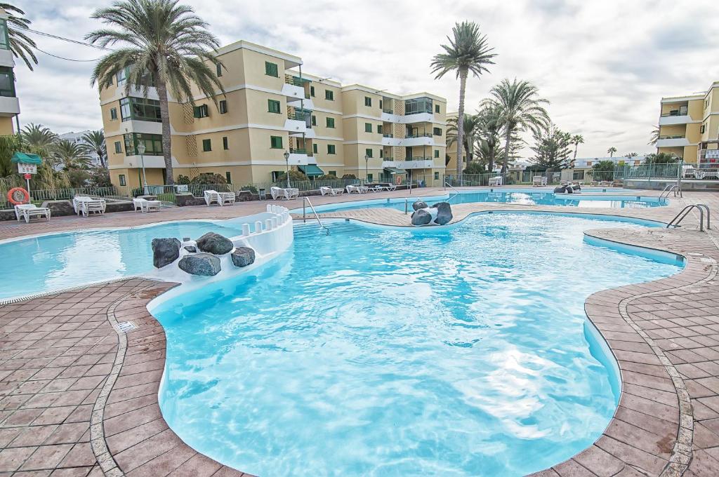 een zwembad in een resort met palmbomen en gebouwen bij Complejo Las Olas in Maspalomas