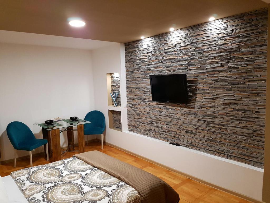 a bedroom with a brick wall with a flat screen tv at Woodstone apartment in Ploieşti