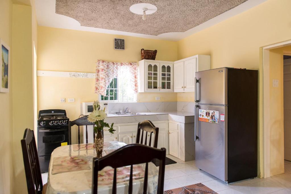 a kitchen with a table and a stainless steel refrigerator at Relax in Sunny Montego Bay, Jamaica in Montego Bay