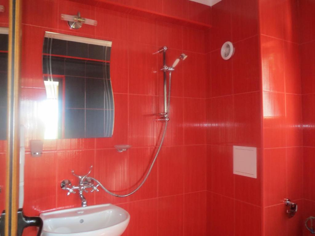 a red tiled bathroom with a shower and a sink at Family Hotel Golden Lion in Primorsko