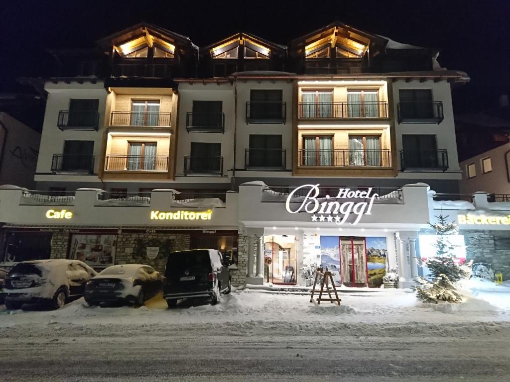 budynek z samochodami zaparkowanymi przed nim w obiekcie Hotel Binggl w mieście Obertauern