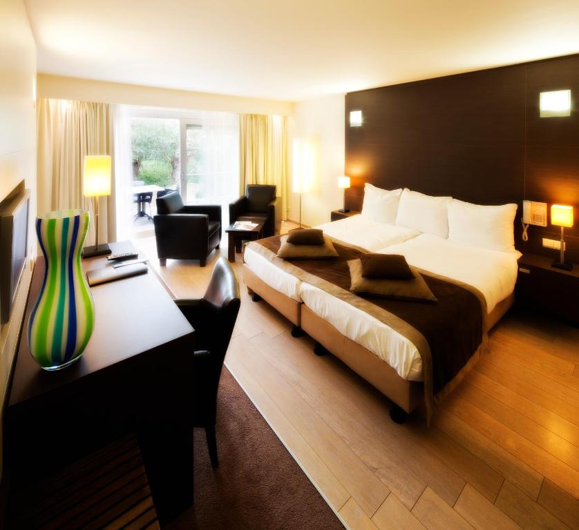 a hotel room with a large bed and a desk at Van der Valk Hotel Drongen in Drongen