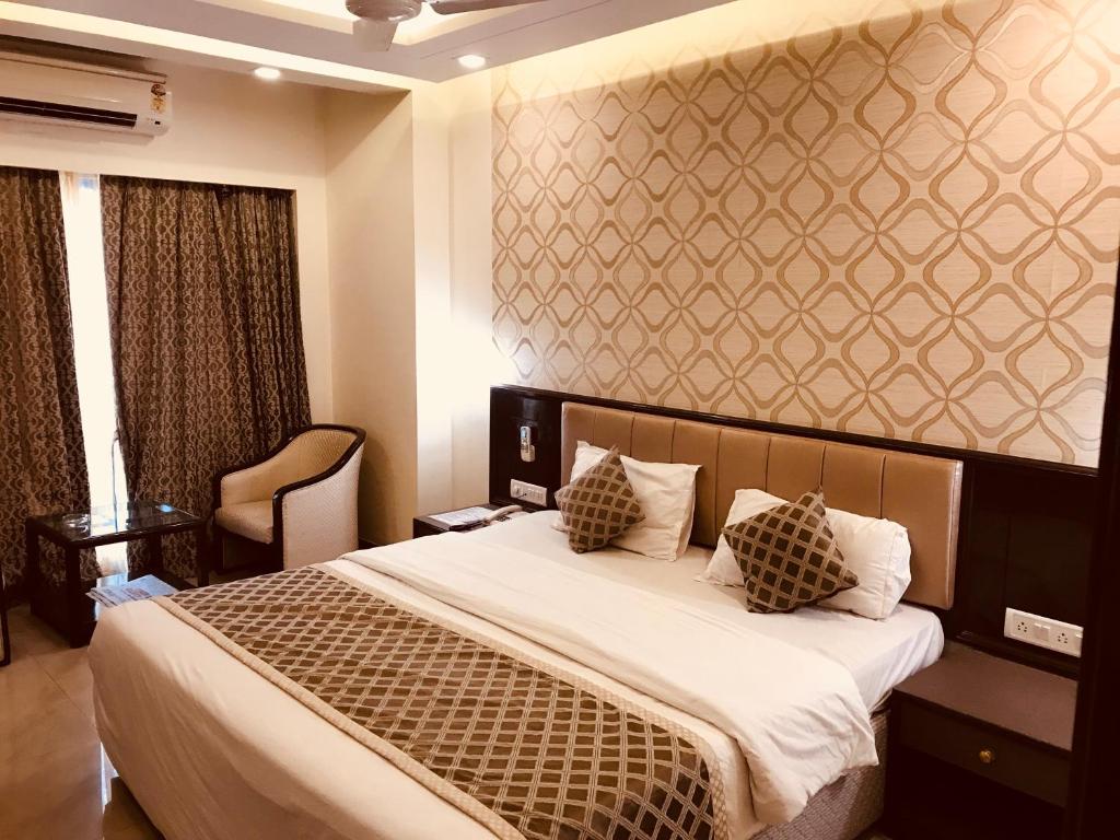 a bedroom with a large bed with white sheets and pillows at Hotel Kohinoor Executive in Pune