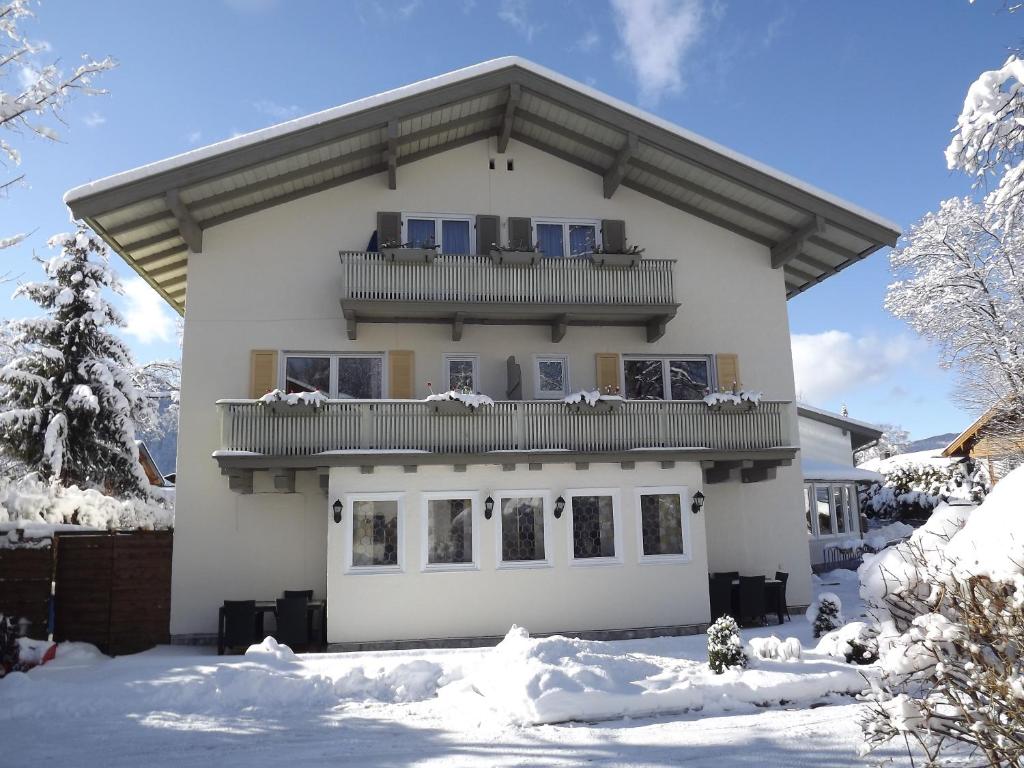 a white house with a balcony in the snow at Hotel Berlin Tegernsee in Rottach-Egern