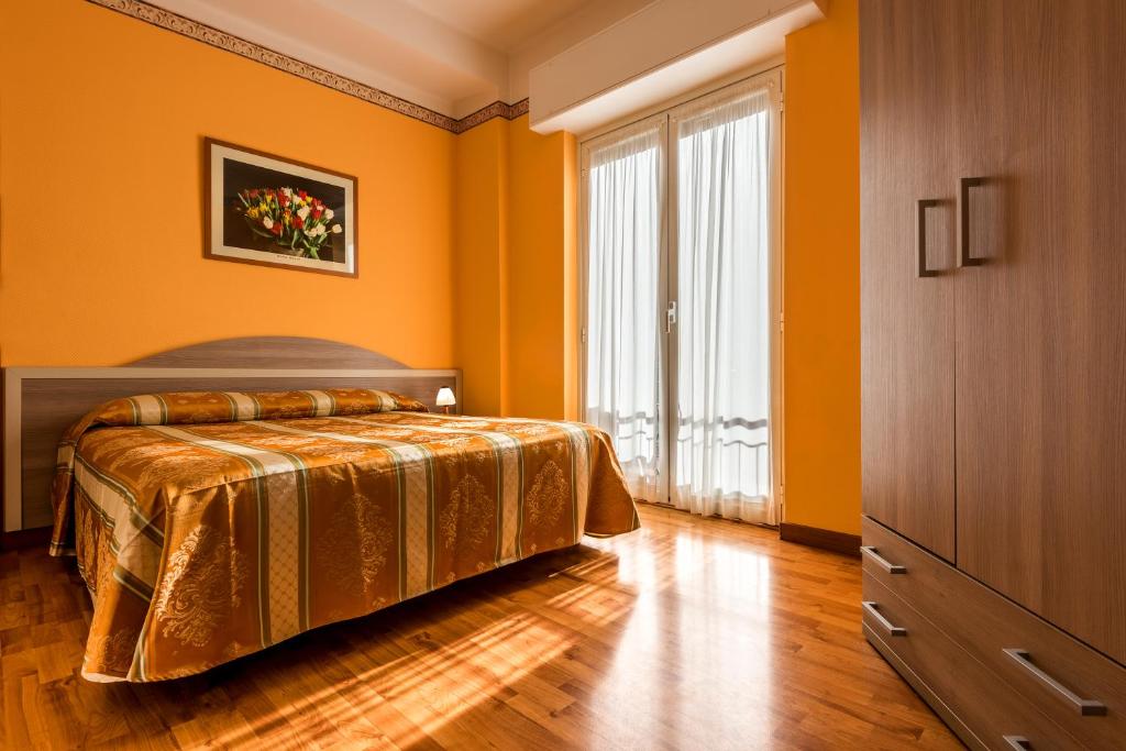 a orange bedroom with a bed and a large window at Hotel Calypso in Ventimiglia