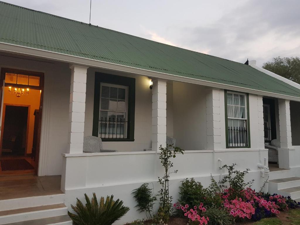 una pequeña casa blanca con techo verde en Uniondale Manor Guesthouse, en Uniondale