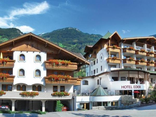 ein großes Hotelgebäude mit Blumen auf den Balkonen in der Unterkunft Hotel Eder in Ramsau im Zillertal