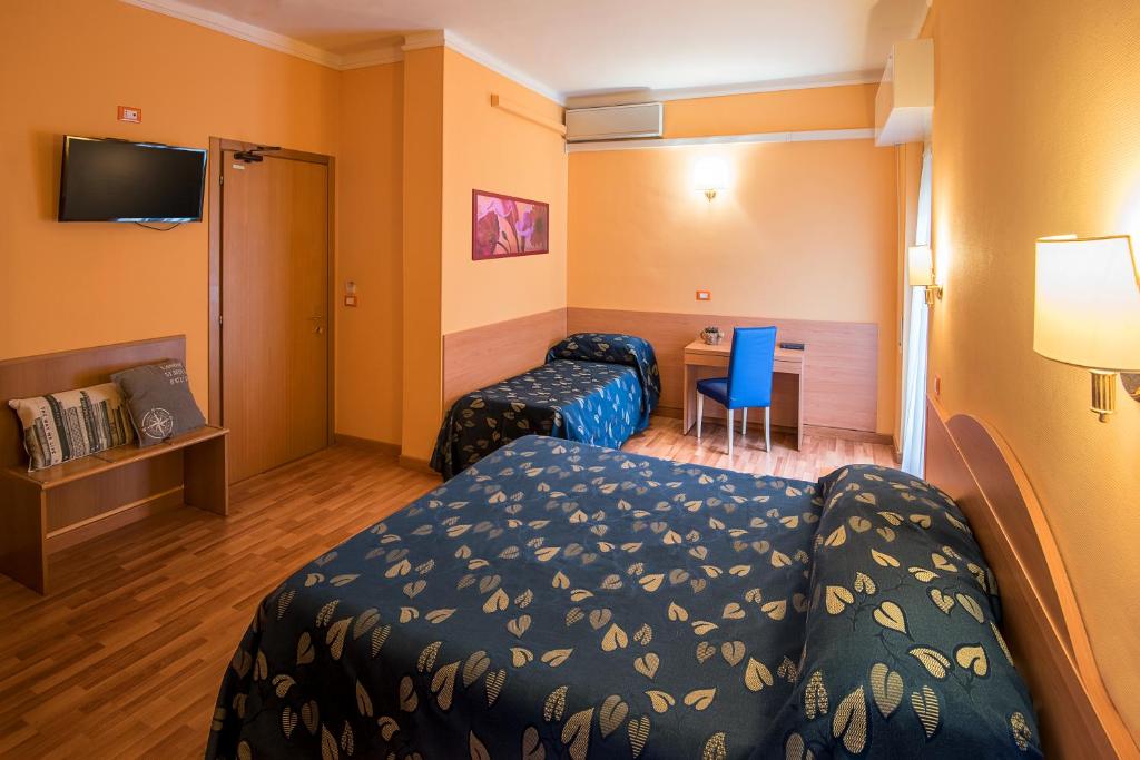 a hotel room with two beds and a desk at Hotel Calypso in Ventimiglia