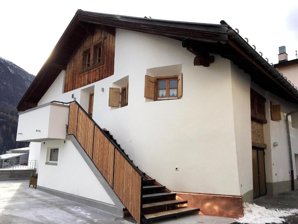a white house with a staircase in front of it at Plazzöl Suol Nr. 5 in Scuol
