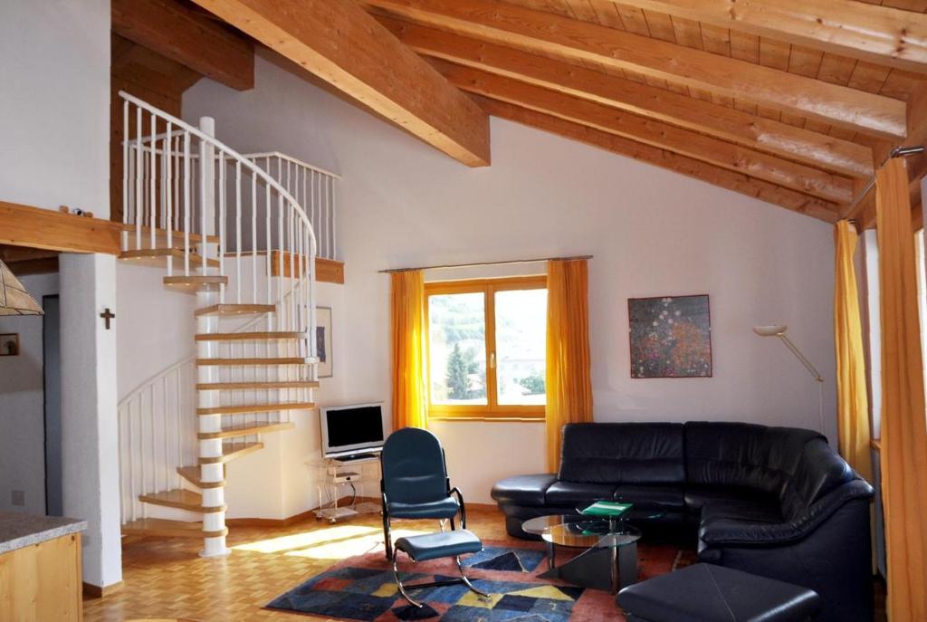 a living room with a black leather couch and a staircase at Pütvia E6 in Scuol