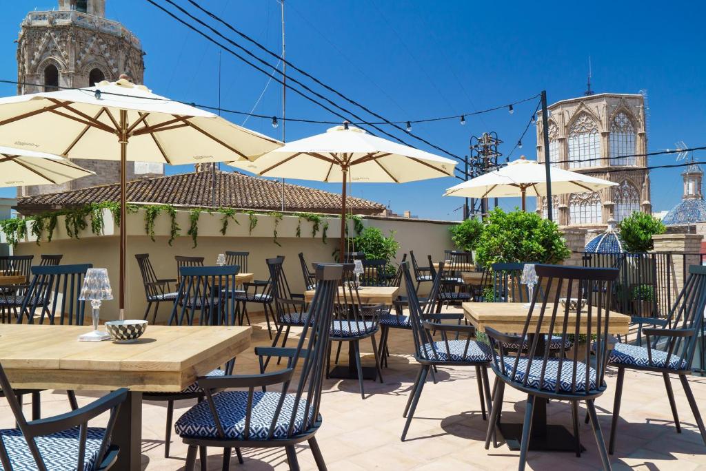 een groep tafels en stoelen met parasols bij The Valentia Cabillers in Valencia