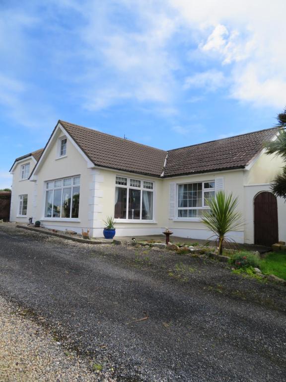 een wit huis met ramen aan een straat bij Lake View Apartment in Belmullet