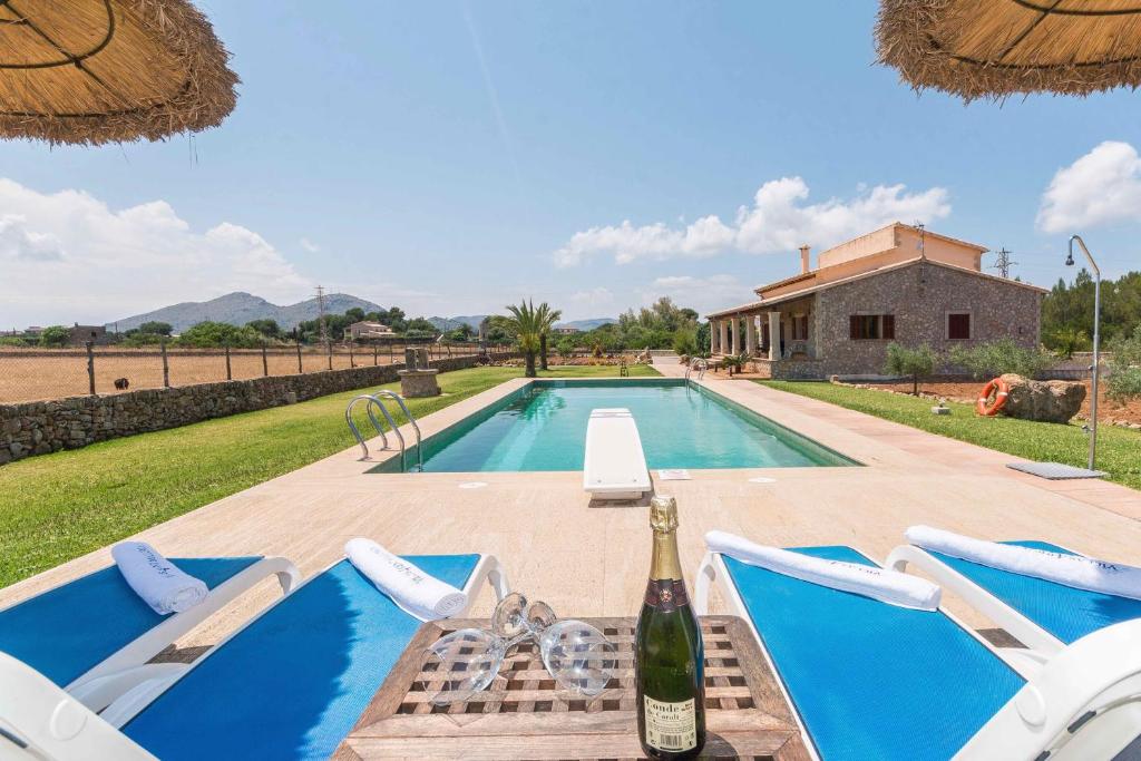 a swimming pool with a bottle of wine next to a house at Can Mosca - Private Pool & Large Garden in Alcudia