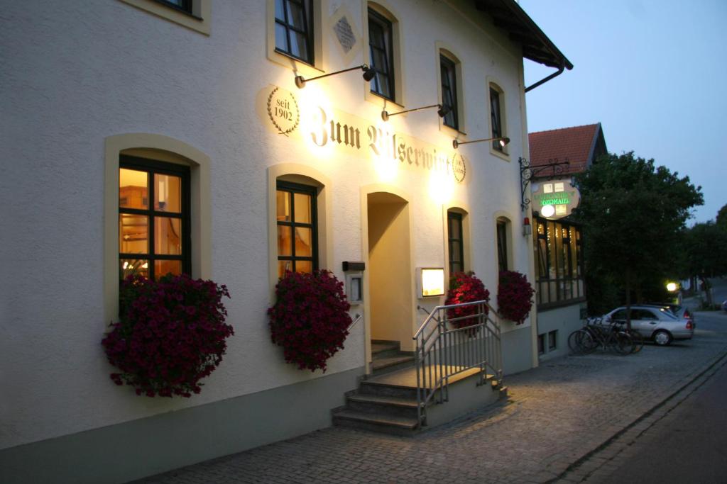 a white building with flowers on the side of it at Hotel - Landgasthof Obermaier Zum Vilserwirt in Altfraunhofen
