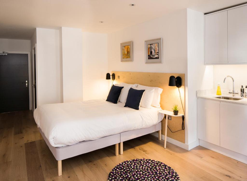 a bedroom with a white bed and a kitchen at Hiding Space Westgate Apartments in Bath