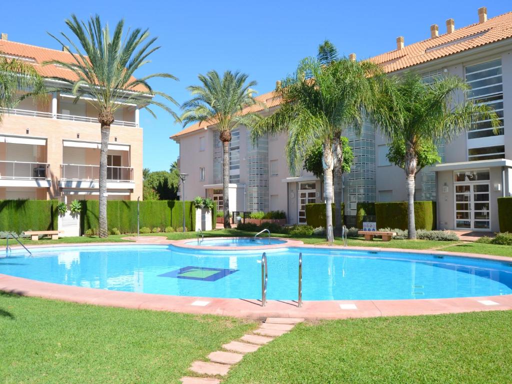 a swimming pool with palm trees in front of a building at Apartamento Golden Gardens in Jávea