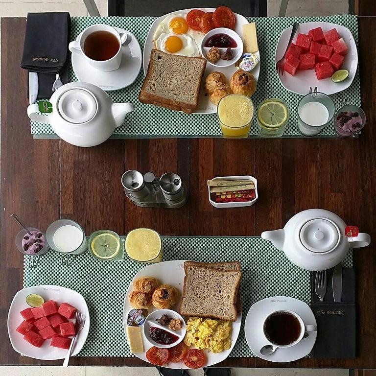 a table with plates of breakfast foods and cups of coffee at The Puncak Lombok in Senggigi