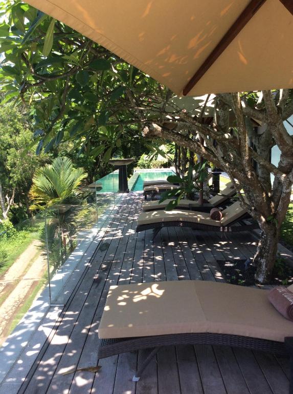 a deck with benches and a tree and a pool at The Puncak Lombok in Senggigi