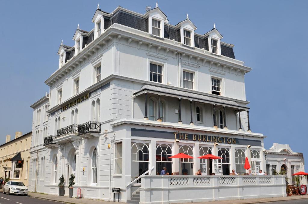 un edificio blanco con sombrillas rojas delante en The Burlington, en Worthing