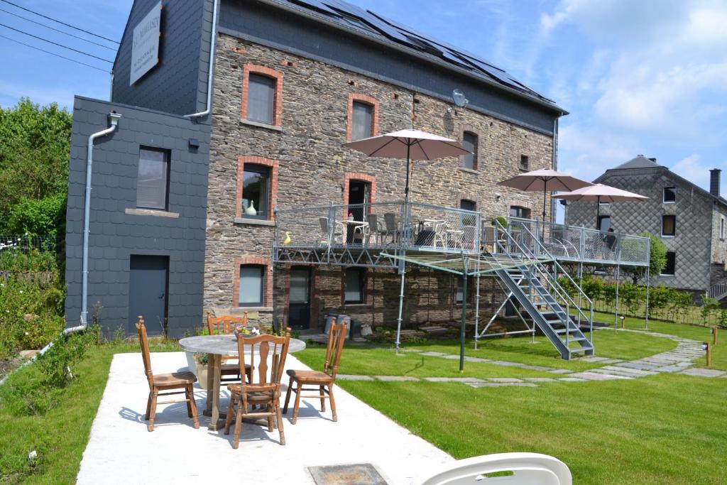 eine Terrasse mit einem Tisch und Stühlen sowie ein Gebäude in der Unterkunft au-magasin in Vielsalm