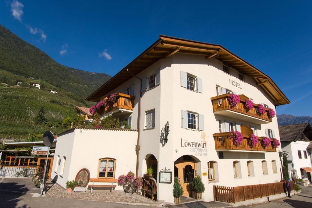 a large white building with flowers on the balconies at Hotel Löwenwirt in Cermes