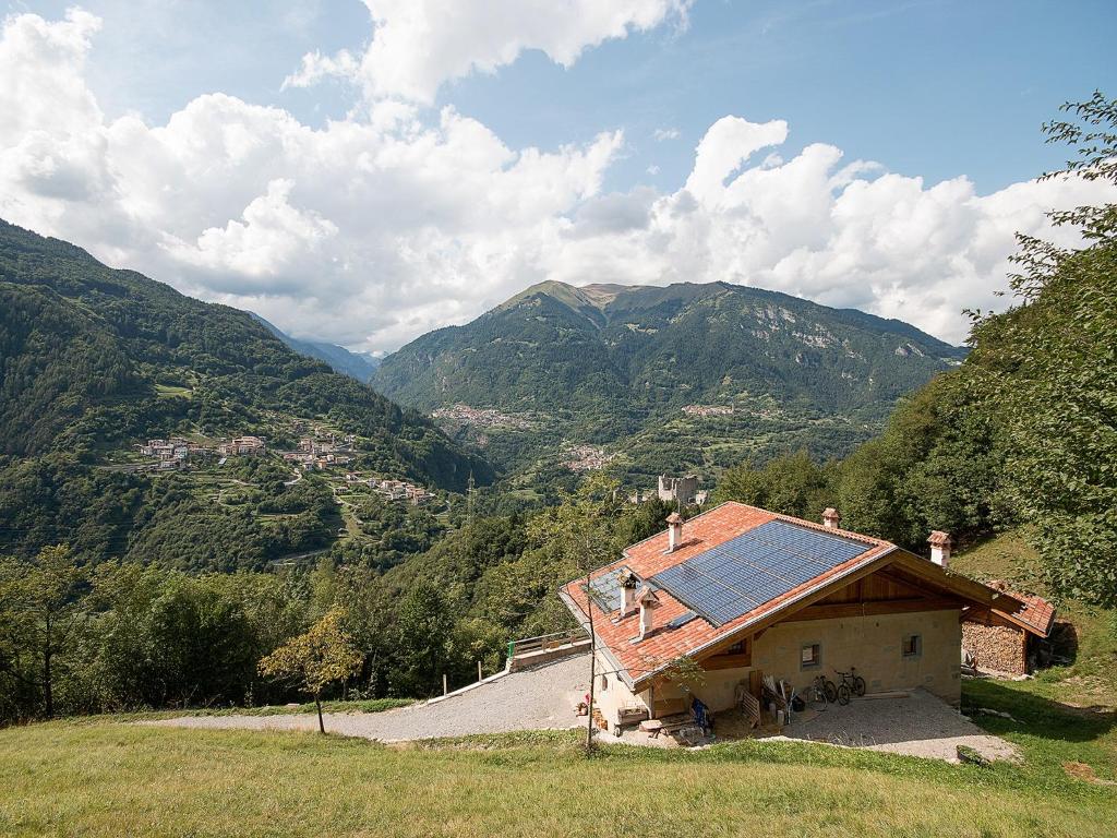 a house with a solar roof with mountains in the background at agriturismo la Meta in Pieve di Bono