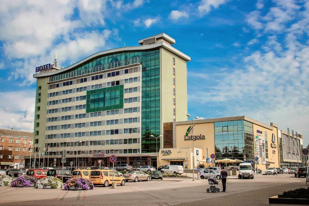 Park Hotel Latgola في داوُجافبيلسْ: مبنى كبير به سيارات تقف في موقف للسيارات