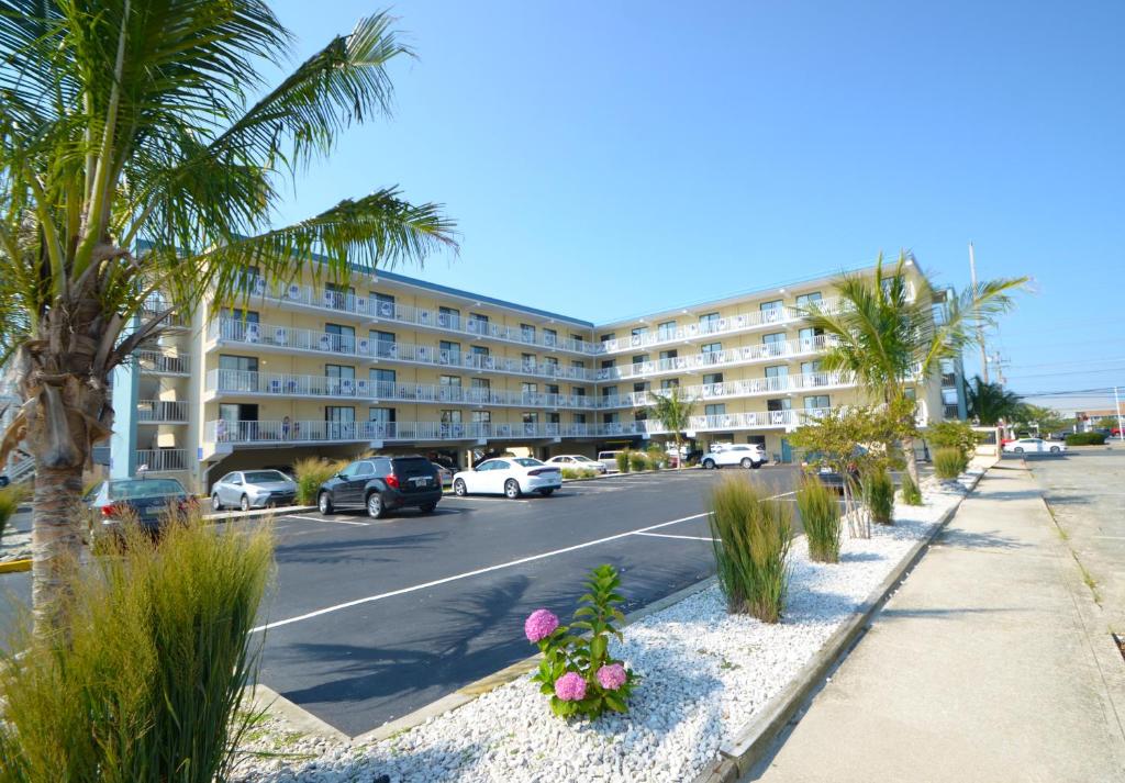 um parque de estacionamento com palmeiras e um edifício em Coastal Palms Inn and Suites em Ocean City