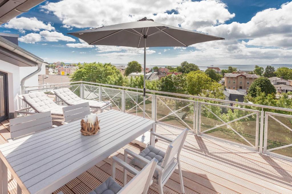 einen Balkon mit einem Tisch, Stühlen und einem Sonnenschirm in der Unterkunft Villa Am alten Kreidebruch, Penthouse *Sea Spirit* in Sassnitz