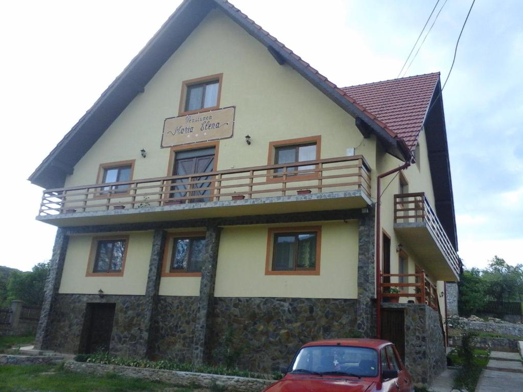 a house with a car parked in front of it at Pensiunea Maria-Elena in Ponoarele