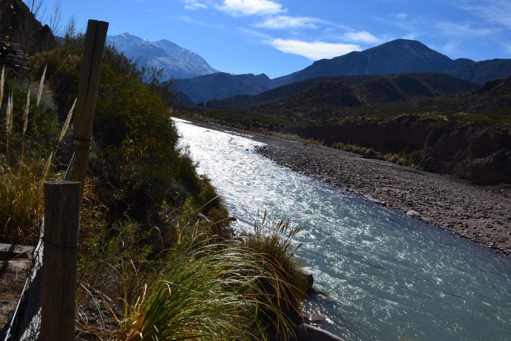 a river with rocks and mountains in the background at Mendoza Sol y Nieve in Potrerillos