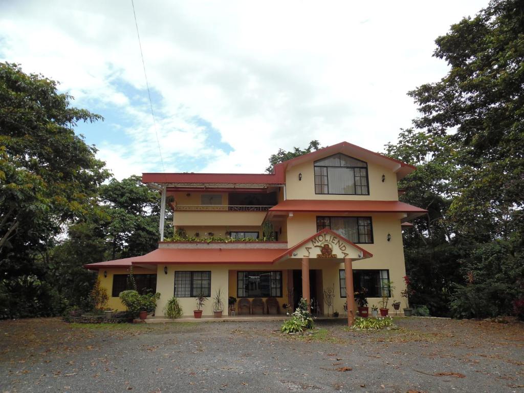 a large yellow house with trees in front of it at Hostal La Molienda in Puyo