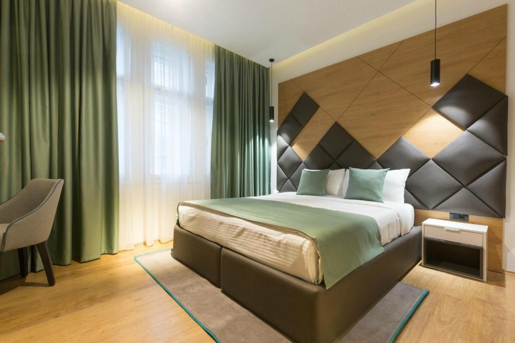 a bedroom with a large bed and a chair at Capital Hotel Garni in Belgrade
