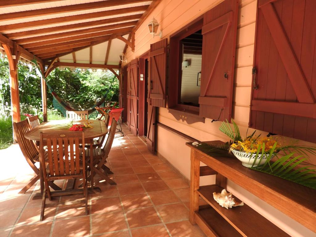 une terrasse couverte avec une table et des chaises. dans l'établissement Villa des Amandiers, à Les Anses-d'Arlet