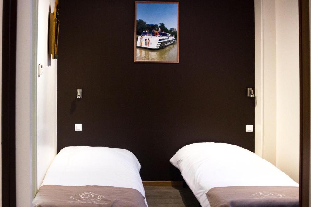 two beds in a room with a picture on the wall at Le Relais Du Canalou in Digoin