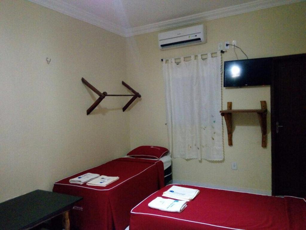 um quarto com duas camas vermelhas num quarto em Pousada Aquino em Sobral